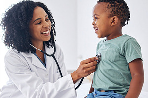 Pediatrician examining a cheerful child with a stethoscope in a, a Health & Medical Photo by DanFLCreativo