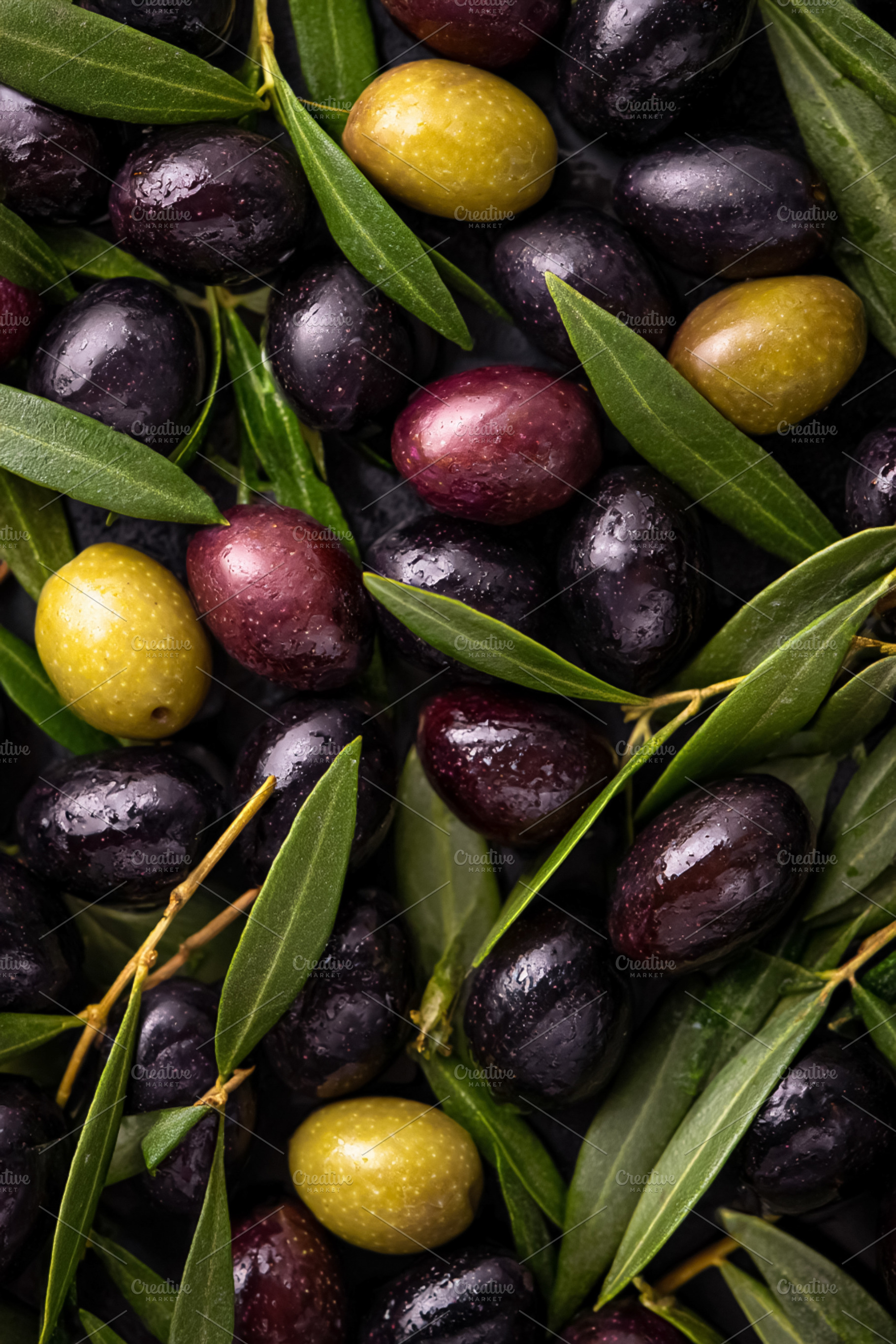 Assorted olives and green leaves creating a rich texture, repres, a Photo by Studio ANNA