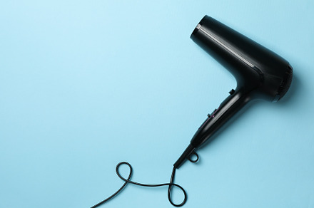 Black hair dryer on blue background, space for text, a Beauty & Fashion Photo by AtlasStudio PRO