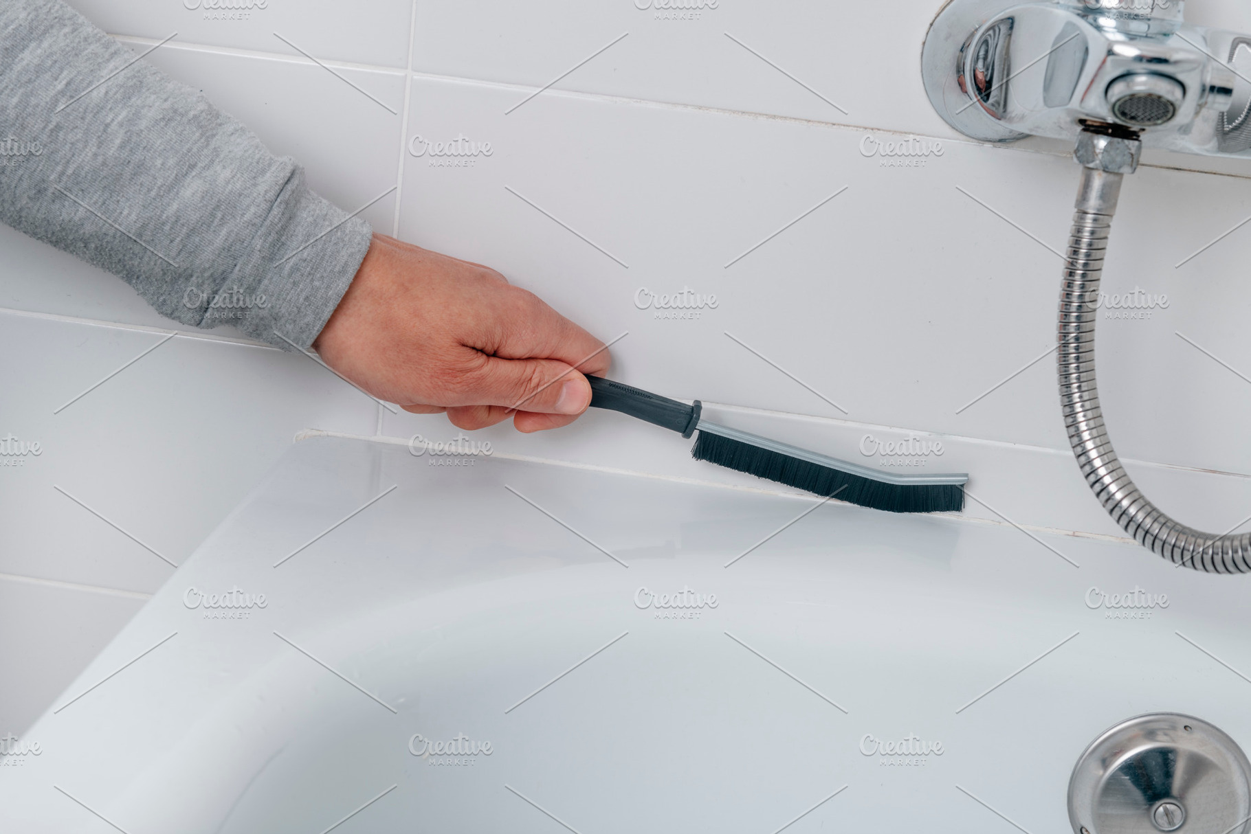 a man cleans the bathtub tile grout, a Photo by Nito