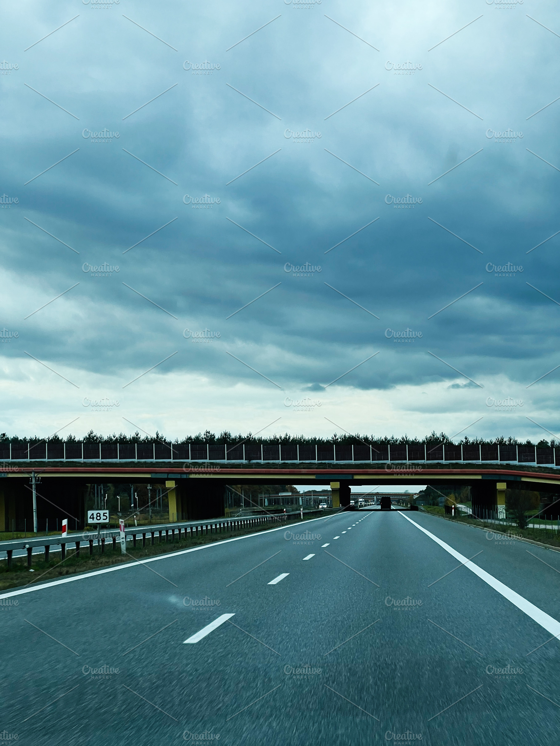 Stormy sky over a highway with an overpass and approaching vehicles during dram, a Photo by AS photostudio
