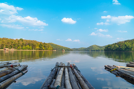 A serene view of bamboo rafts floating on calm lake, surrounded by lush green h, a Nature Photo by a454