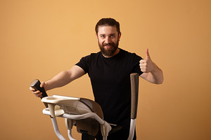 Smiling man in black shirt using elliptical machine and showing, a Person Photo by Ales Munt