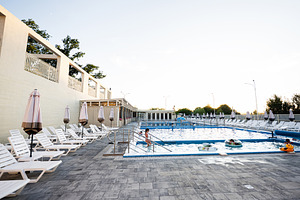 Outdoor swimming pool with lounge chairs and visitors enjoying a sunny day, a Photo by AS photostudio