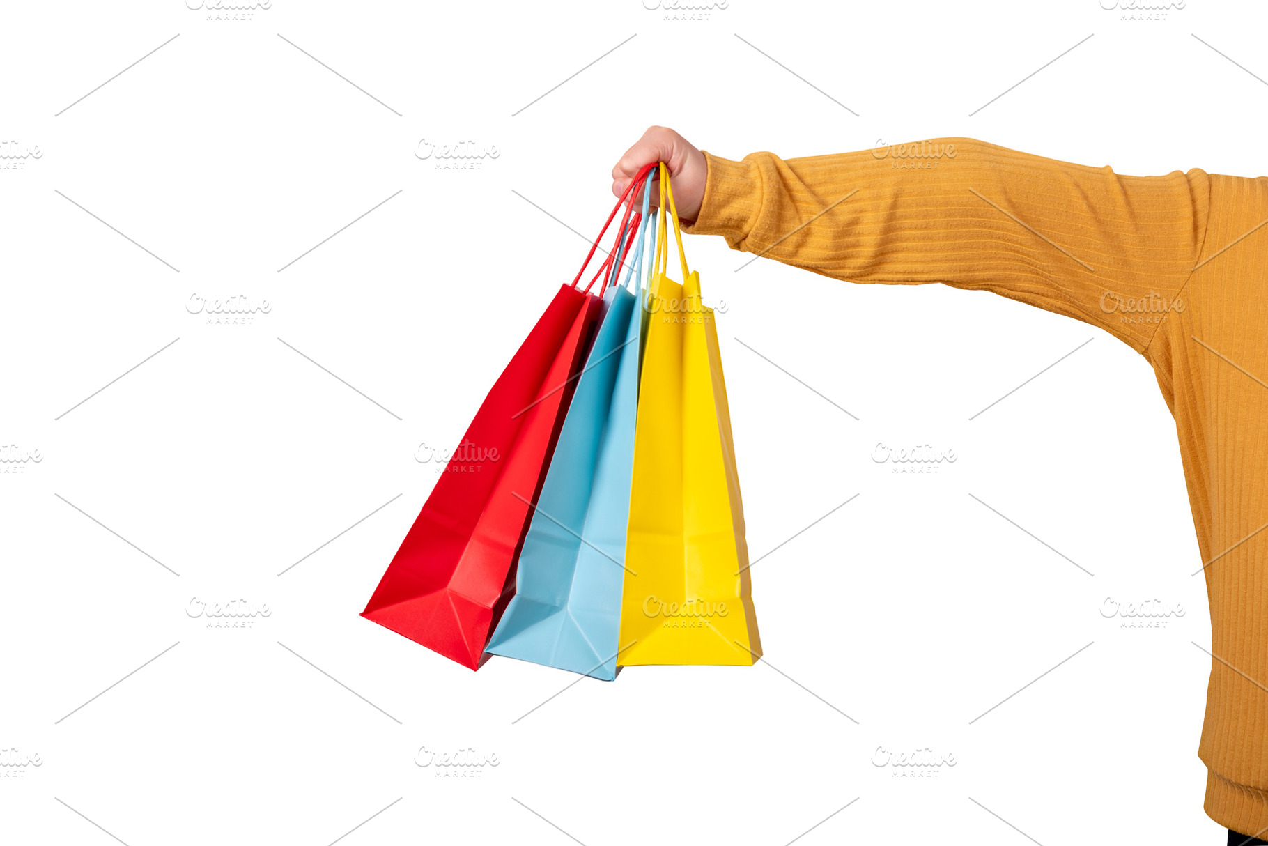 A person in a yellow sweater holding red, blue, and yellow shopp, a Beauty & Fashion Photo by Ales Munt