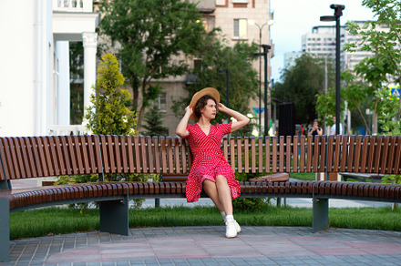 Woman adjusts straw hat while seated