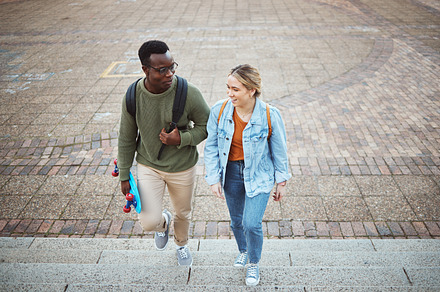 University, students talking and friends, education and campus, study discussion with walk and talk together with learning. Scholarship, college and communication with black man and woman on steps, a Photo by Peopleimages.com