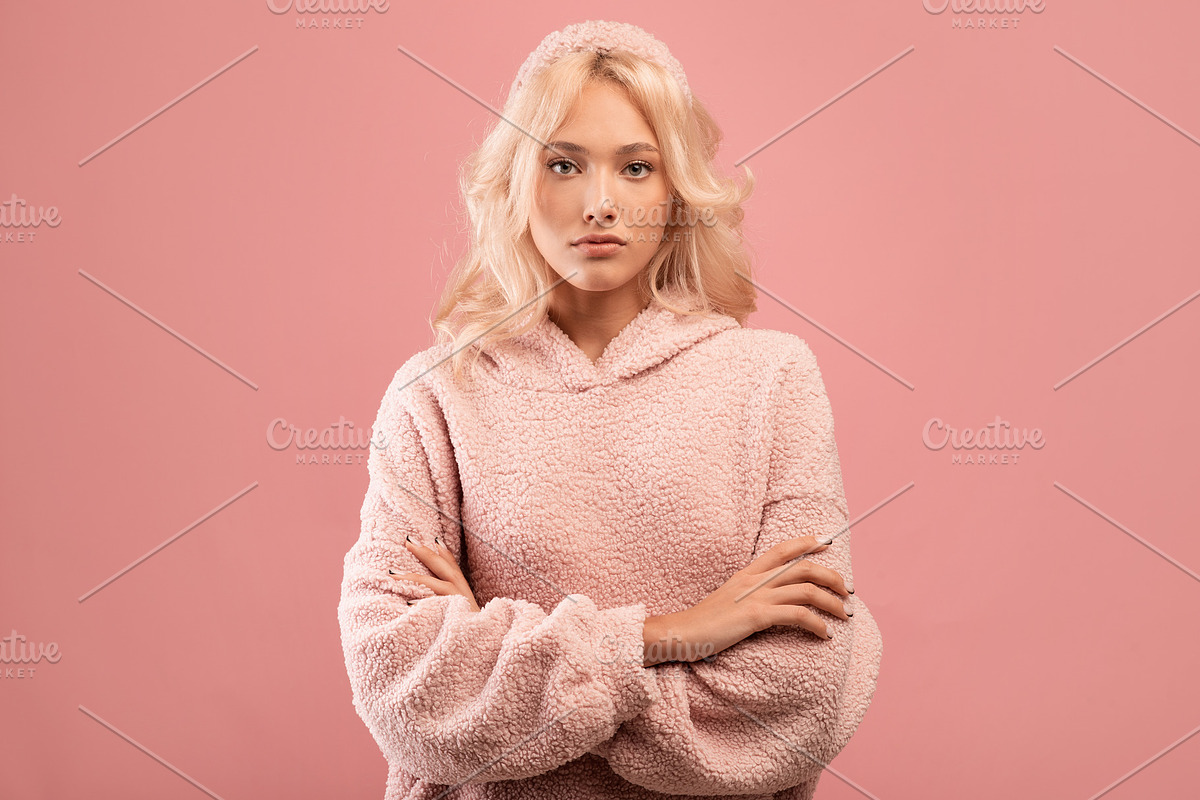 Serious stylish lady looking at camera and posing with folded arms over pink st, a Photo by Prostock-Studio (Photo 2 of 2)