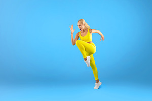 Fit woman running and screamng at blue studio background, a Photo by Prostock-Studio