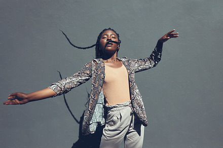 Fashion, style and trendy black woman against a gray background wall in a city, town and downtown. Street beauty model with funky, cool and hipster hair in edgy motion or movement expression outdoors, a Photo by Peopleimages.com