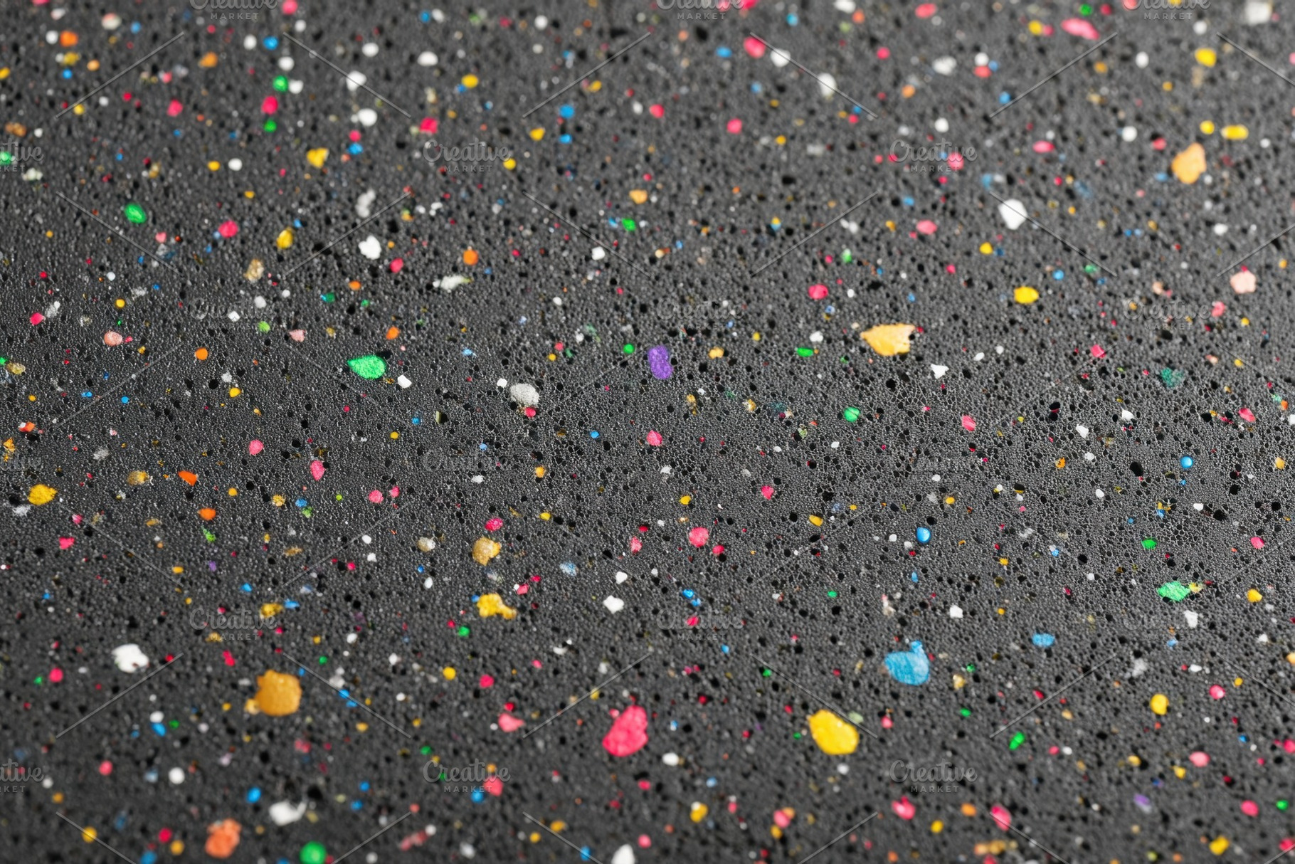 Colorful speckled particles on dark surface, a Background Photo by AlyaAnd