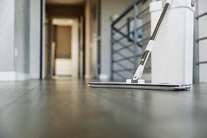Cleaning supplies: mop and bucket with wringer on wooden laminate floor, a Business Photo by Lenor4ik