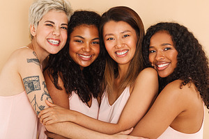 Four smiling diverse women embracing, a Person Photo by Artem Varnitsin