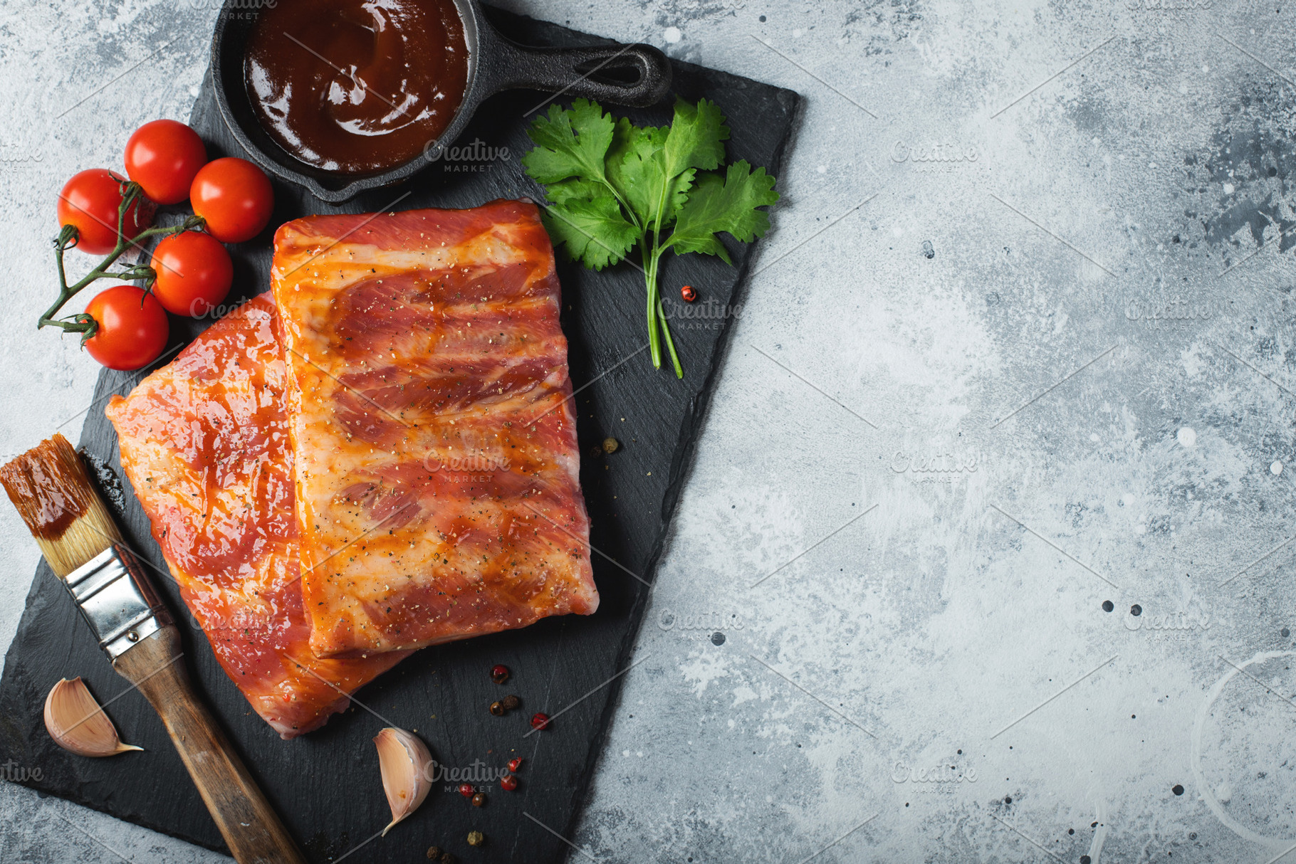 Ready for BBQ raw pork spare ribs with barbecue sauce. Black background. Top vi, a Food & Drink Photo by Budarinphoto