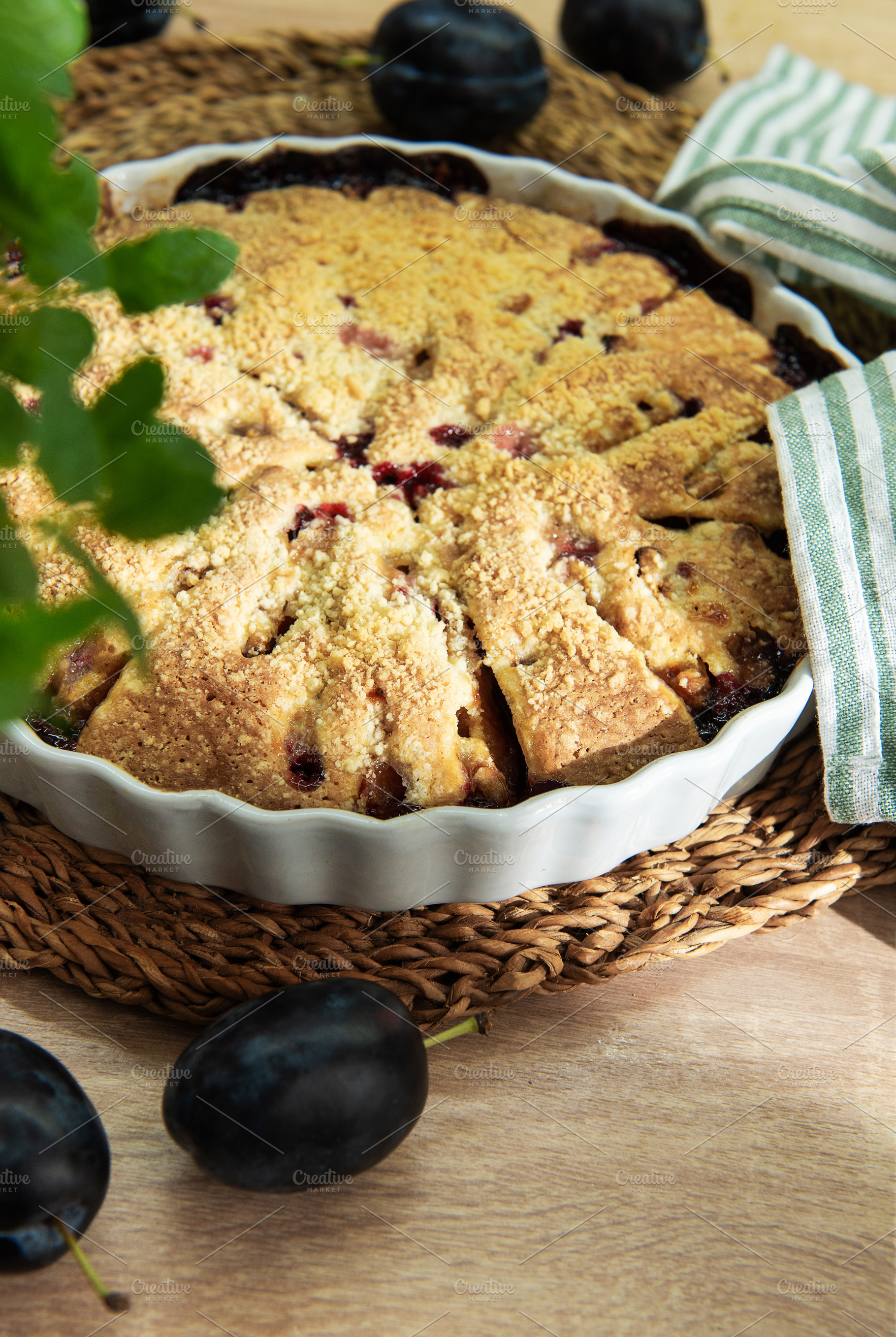 Baked plum dessert with crumb topping on rustic table, a Food & Drink Photo by Olena Rudo