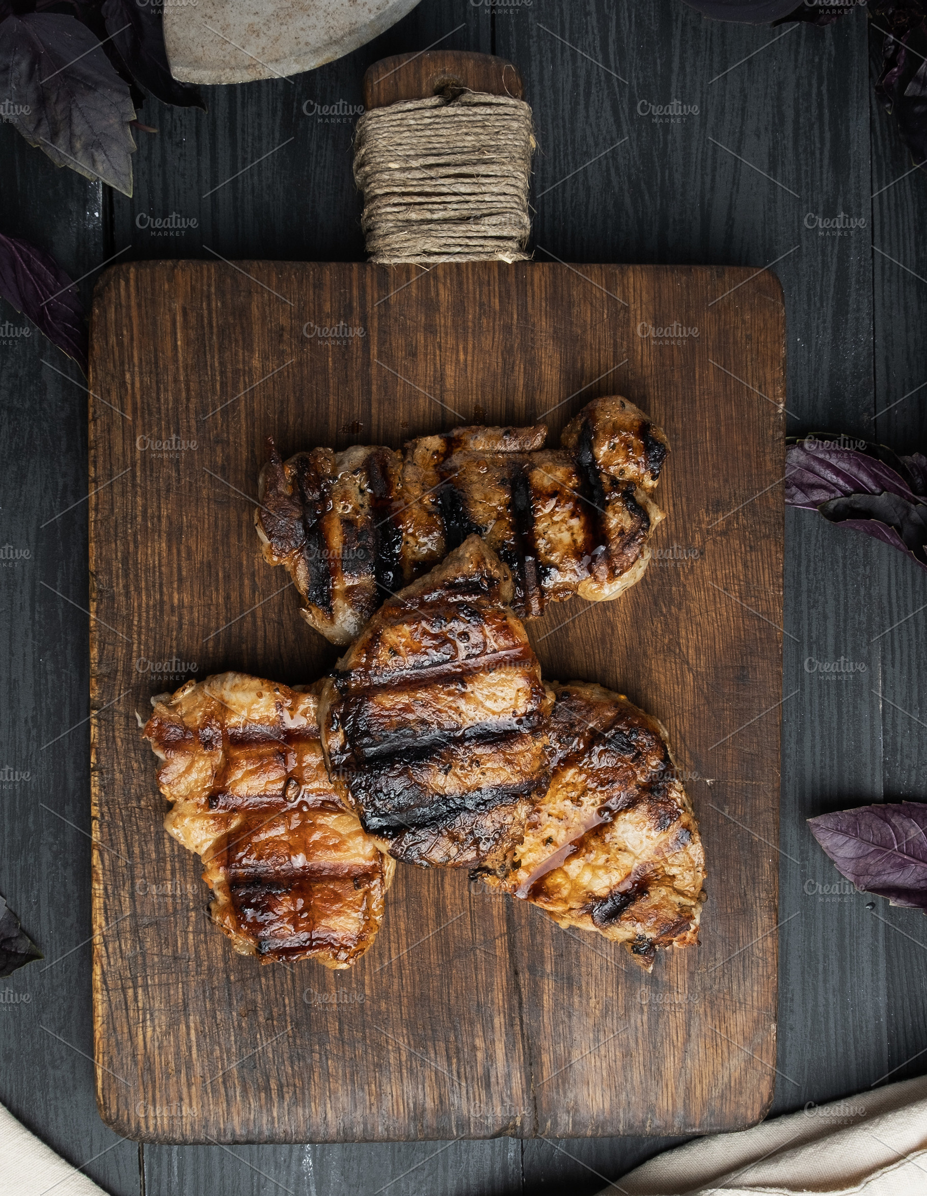 Grilled steaks on a wooden board, black background, a Food & Drink Photo by ndanko