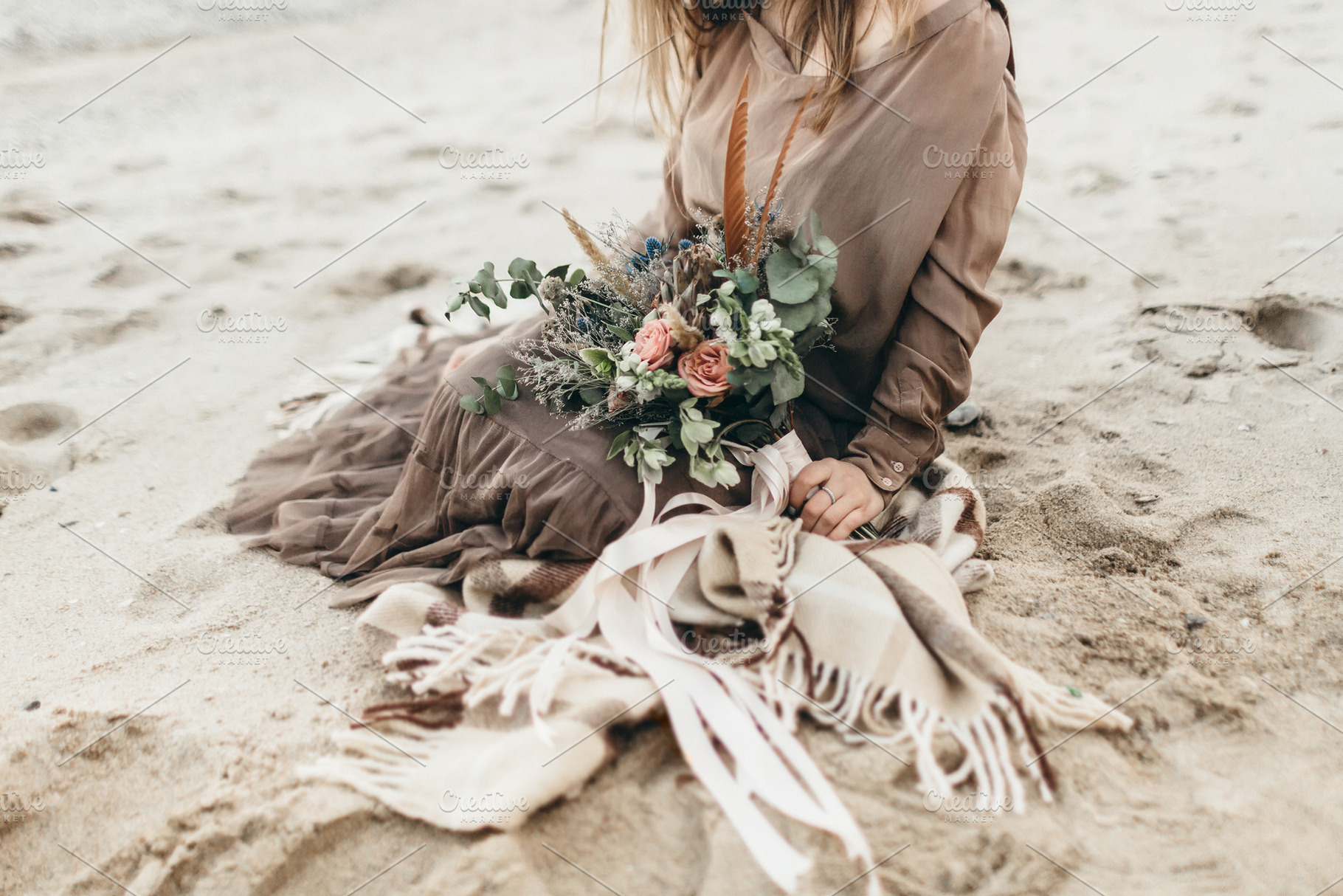 Bride in brown clothes with a rustic bouquet sit on the sand artwork country, a Person Photo by Stahov