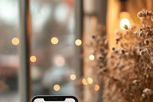 A smartphone iPhone mockup with a blank screen placed on a wooden table next to, an iPhone Mockup by Textures & Backgrounds