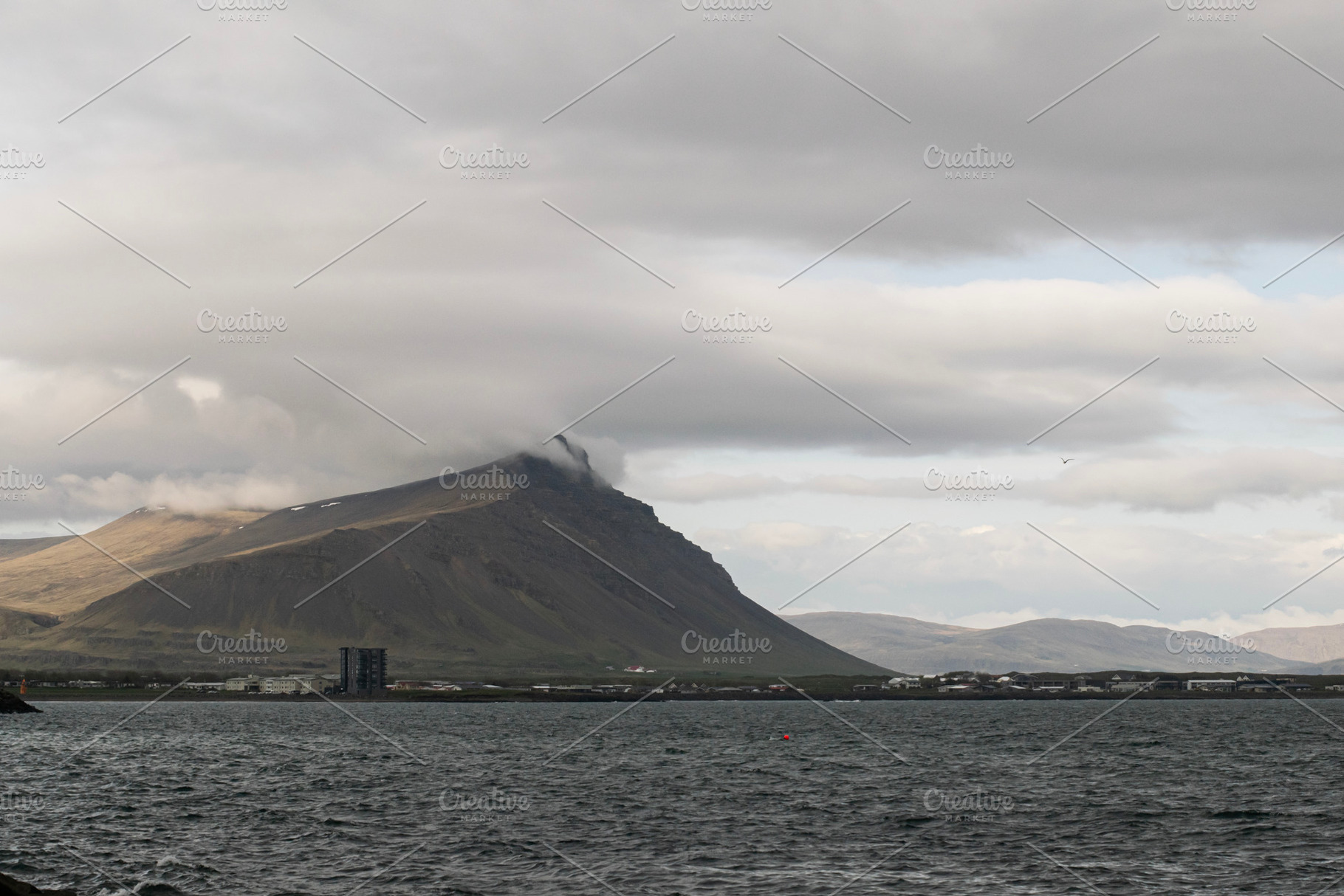 Misty mountain landscape and ocean in Akranes, Iceland under cloudy skies, a Photo by AS photostudio