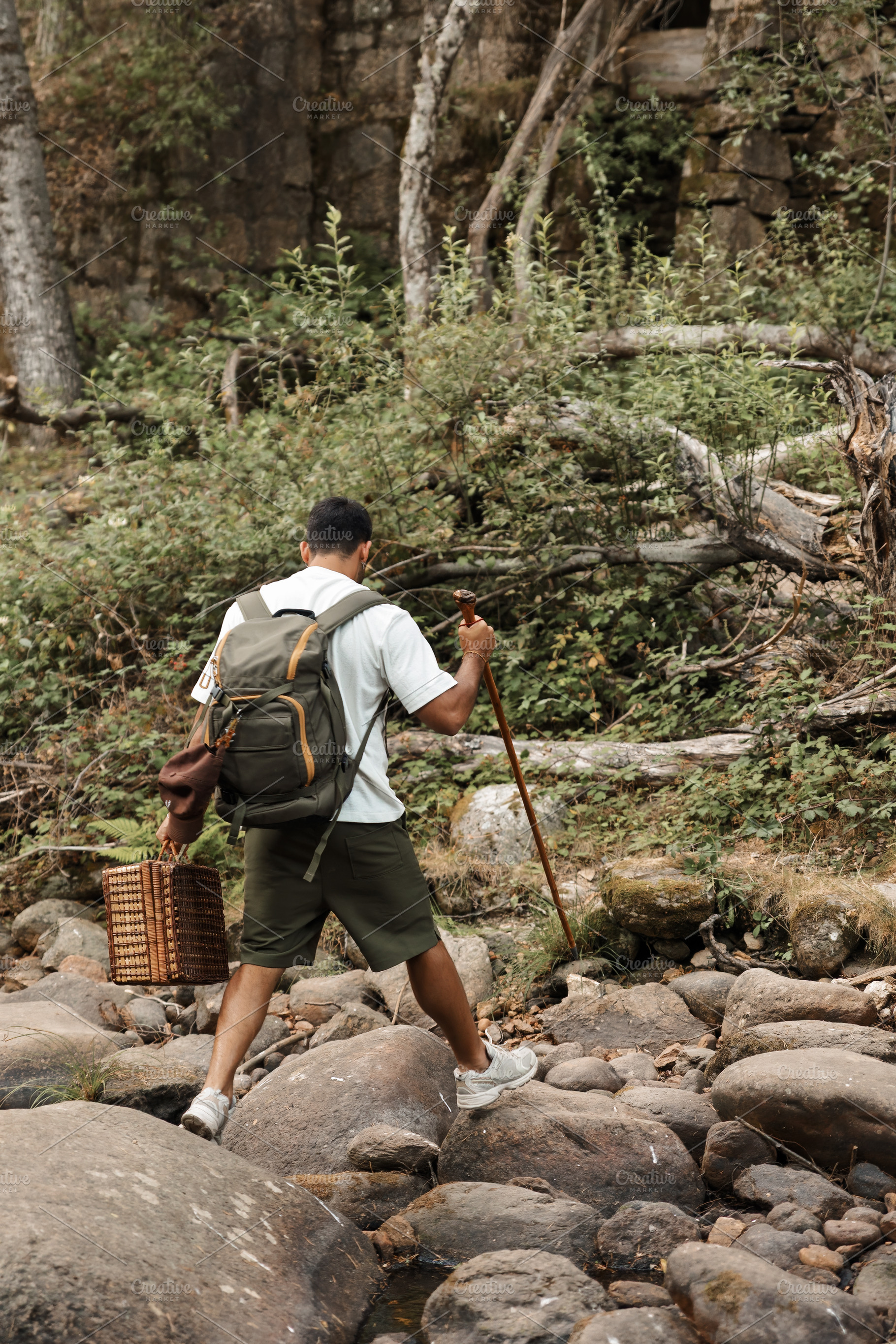 Man with backpack crossing rocky riv, a Person Photo by Perpis