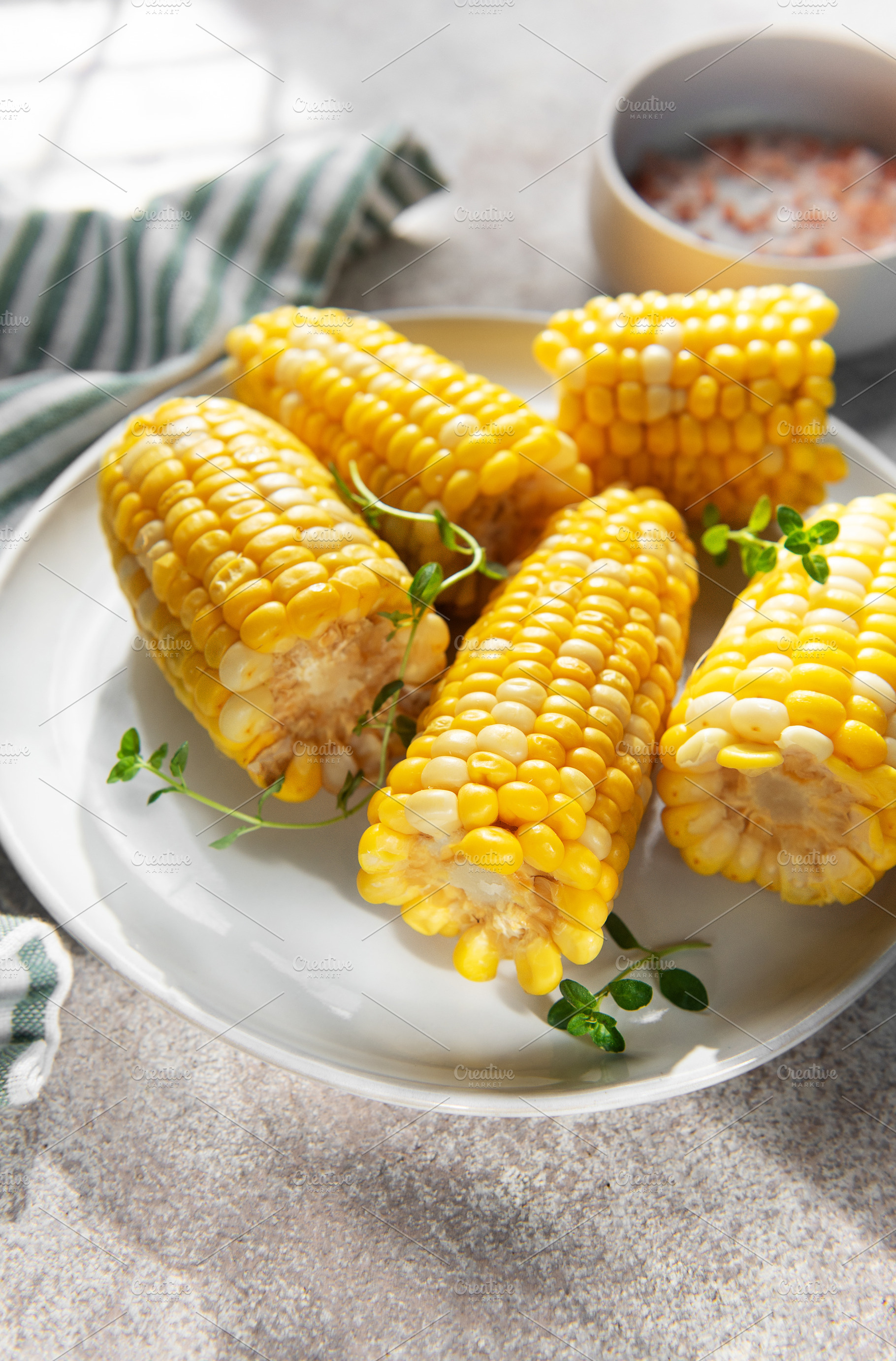 Boiled sweet corn on the cob serving with fresh herbs, a Food & Drink Photo by Olena Rudo