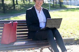 Businesswoman working on laptop in sunny park, a Photo by RF Images