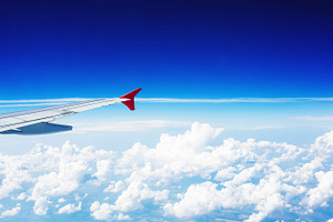 Wing of an airplane above clouds containing wing, airplane, and cloud