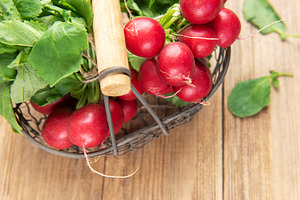 Fresh radishes in basket on wooden background, a Food & Drink Photo by Olena Rudo
