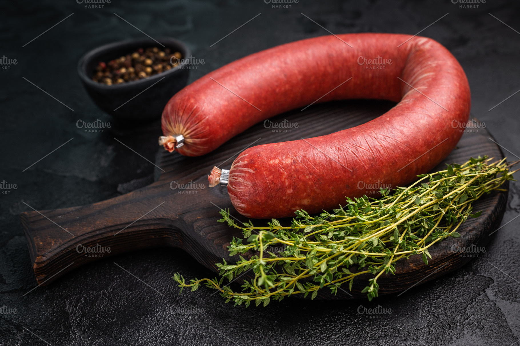Raw Turkish sucuk (sujuk) on a dark rustic board with fresh thym, a Photo by composter-box@mail.ru