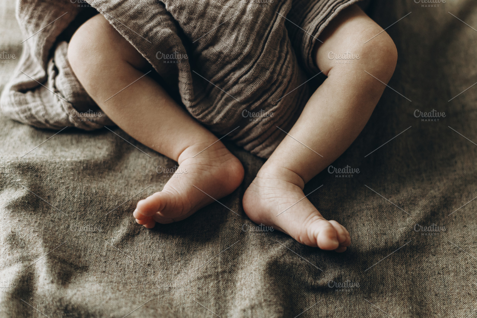 Adorable little baby feet close up in blanket on brown bed. Adop, a Person Photo by Sonjachni