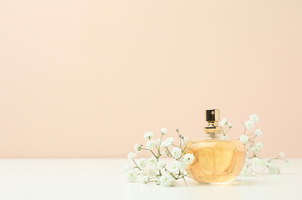 Perfume and flowers against beige background, space for text, a Beauty & Fashion Photo by AtlasStudio