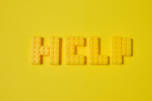 The word HELP, made from yellow toy blocks, is placed on a yello, an Abstract Photo by ndanko
