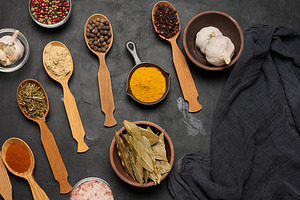 Various ground spices in wooden spoons, peppercorns on dark tabl, a Food & Drink Photo by ndanko