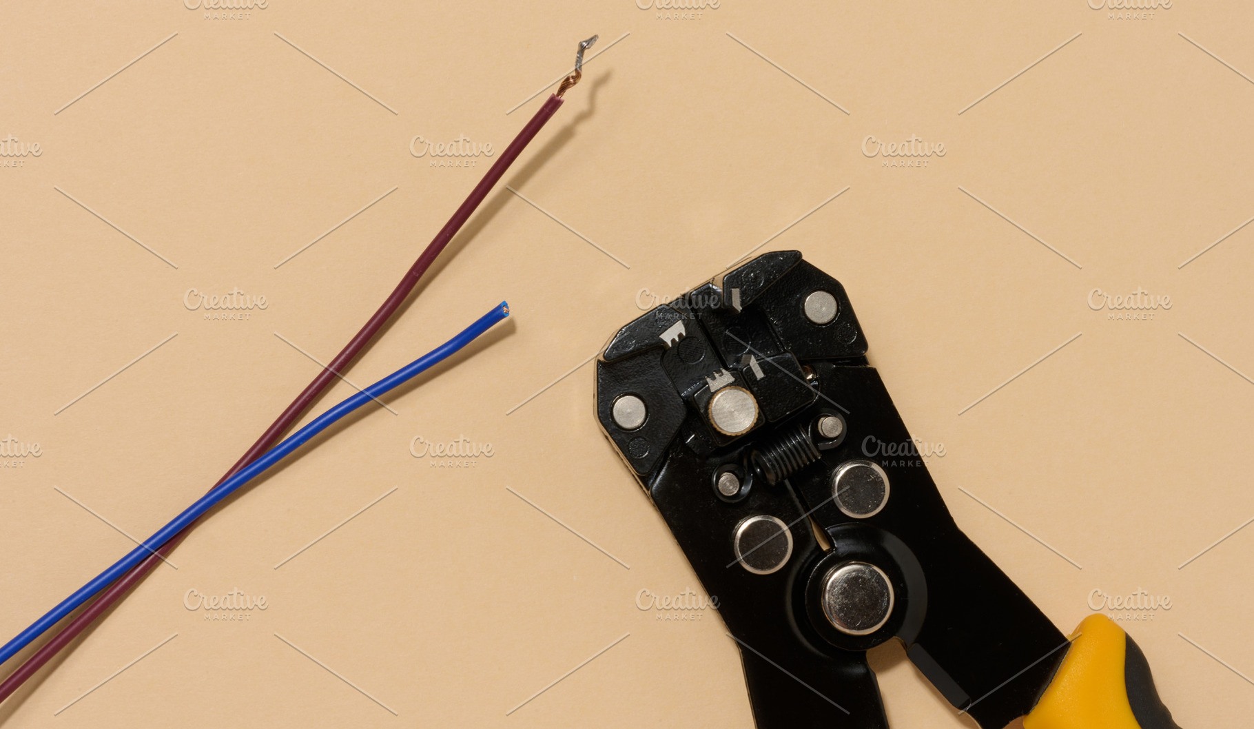 Wire stripper lies next to two cut electrical wires red and blue, a Technology Photo by ndanko