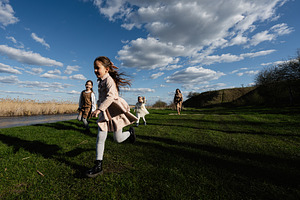 Children running and playing together outdoors along a riverbank on a sunny day, a Person Photo by AS photostudio