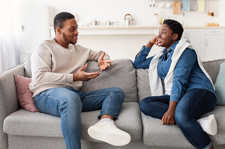 Black couple talking and spending time together sitting on couch, a Photo by Prostock-Studio