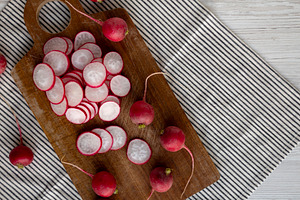 Raw Red Radish Slices on a Cutting Board, top view. Space for te, a Food & Drink Photo by LiudmylaChuhunova