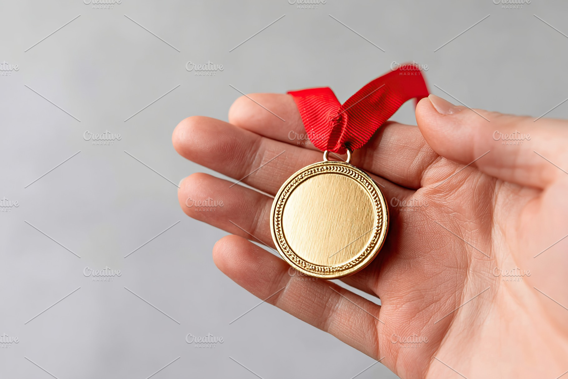 Medal with red ribbon held in hand, symbolizing achievement and recognition in, a Sports & Recreation Photo by AlyaAnd