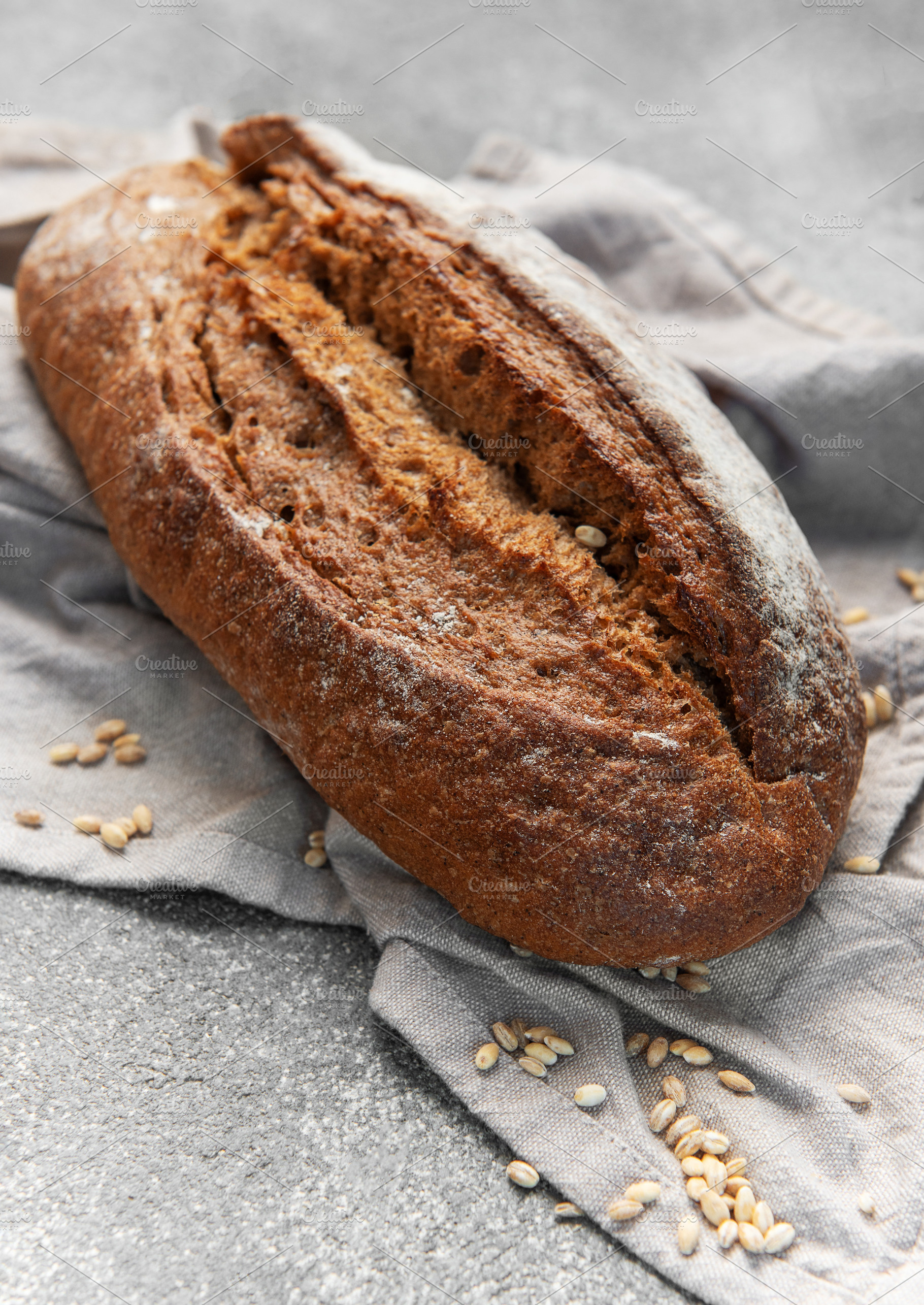 Fresh baked rustic dark bread loaf on towel, a Food & Drink Photo by Olena Rudo