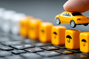 Yellow car and insurance cubes on a keyboard demonstrating protection and cover, a Photo by AS photostudio
