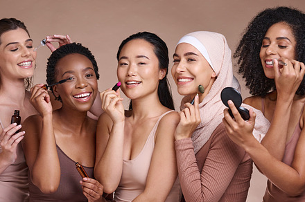Face, skincare makeup and group of women in studio on a brown background. Beauty portrait, diversity and female models with cosmetics, products or lipstick, jade roller or serum, lip gloss or mascara, a Photo by Peopleimages.com
