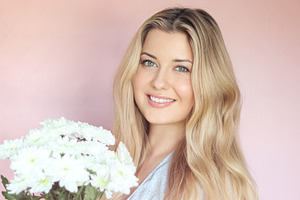 Holding white chrysanthemums, the smiling woman poses against a, a Person Photo by Studio ANNA