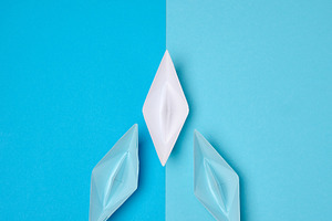 A white origami paper boat symbolizing leadership leads two blue, a Business Photo by ndanko