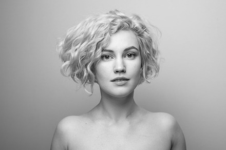 Headshot of gorgeous attractive young lady with curly hair smiling. Black and w