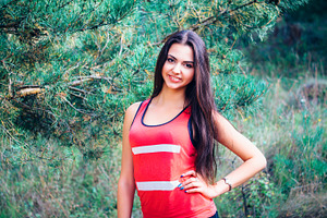 Young beautiful brunette model posing in the sports image of the park against