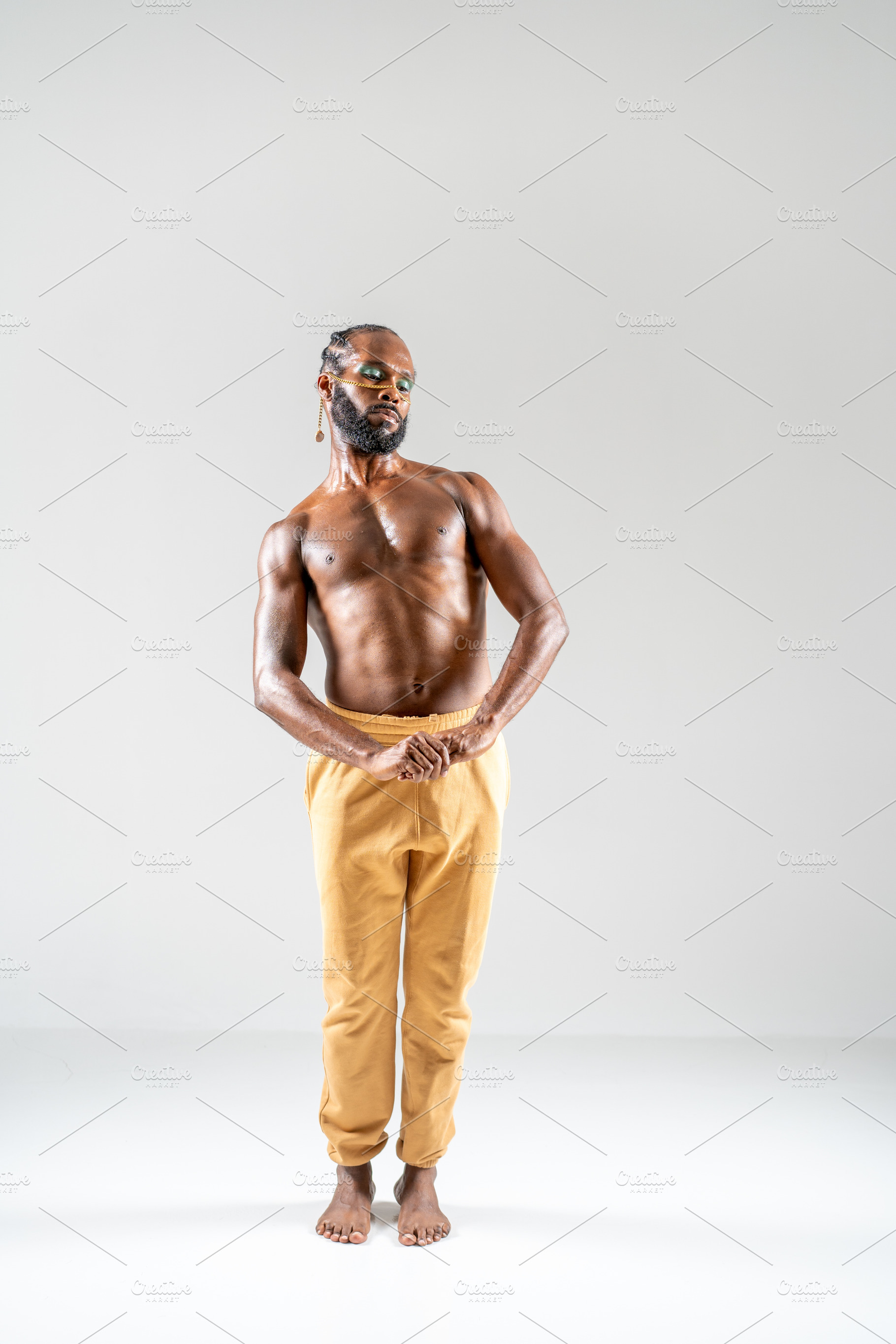 Shy black shirtless gay model holding hand while posing in gray studio, a Person Photo by andreonegin market
