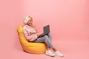Freelance career. Happy young woman working with laptop computer, sitting in be, a Photo by Prostock-Studio