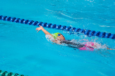 Swimmer child swims backstroke swimming style in a race swimming