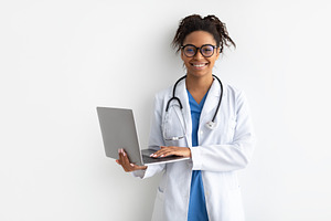 Portrait of black female medical practitioner holding laptop, a Photo by Prostock-Studio