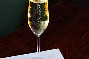 Glass of sparkling wine with rising bubbles on a wooden table, c, a Photo by Studio ANNA